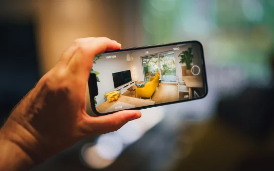 A Hand Holding A Phone With A Screen Showing A Yellow Couch And A Yellow Sofa