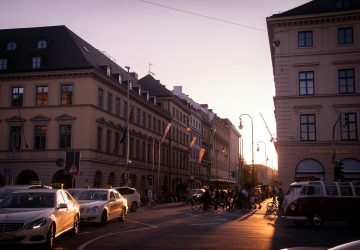 a group of people riding bicycles on a street with buildings and a street light