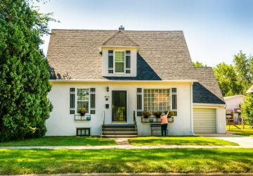 a house with a lawn and a woman standing in front of it